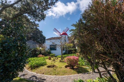 a garden with a windmill in the background at WelcomeBuddy - Casa do Moinho Garden & Sea Retreat in Ponta Delgada