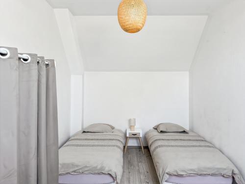 a bedroom with two twin beds and a pendant light at Le refuge in Montoire-sur-le-Loir