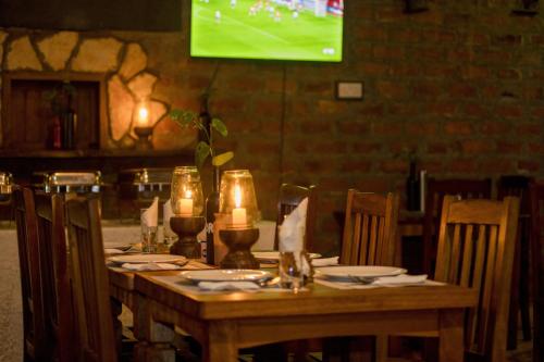 a wooden table with candles and plates and a television at Tusubira village in Jinja