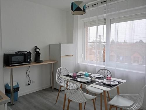 une cuisine avec une table et des chaises et un micro-ondes dans l'établissement Le petit nid Béthunois, à Béthune