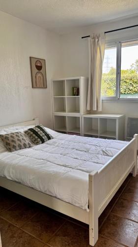- un lit blanc dans une chambre avec fenêtre dans l'établissement Villa L'orée du bois Provence, à Puget-sur Argens