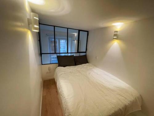 une petite chambre avec un lit et une fenêtre dans l'établissement Paris 9e Loft, à Paris