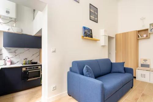 un salon avec un canapé bleu dans une cuisine dans l'établissement Paris 9e Loft, à Paris
