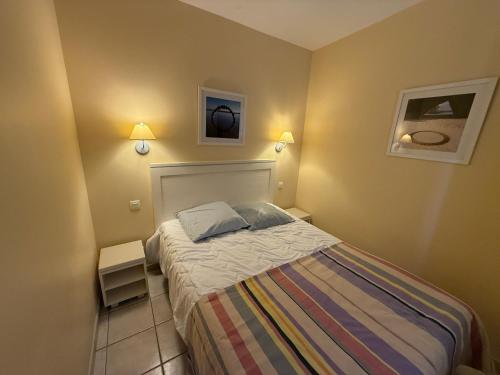 - une petite chambre avec un lit et deux lumières dans l'établissement Charmant appartement T2 en rez de jardin terrasse face mer 4 personnes, à Les Sables-dʼOlonne