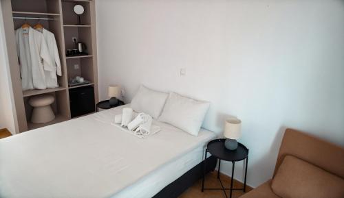 a bedroom with a bed with white pillows and a chair at Sandy Beach in Agia Marina Aegina