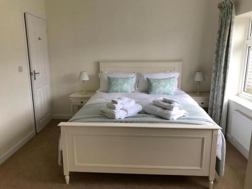 una camera da letto con un letto bianco con asciugamani sopra di Pen Y Frith Bungalow a Prestatyn