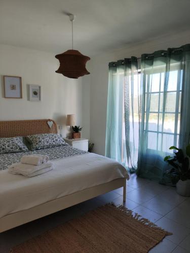a bedroom with a bed and a large window at CasaDizoko in Odeceixe