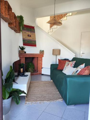 a living room with a green couch and a fireplace at CasaDizoko in Odeceixe