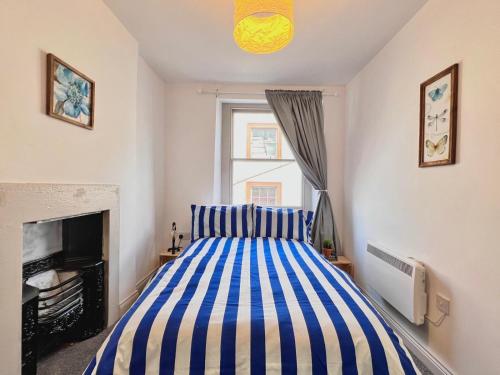 a bedroom with a striped bed and a fireplace at Little Dockray Two-Bedroom Apartment Centre of Penrith in Penrith