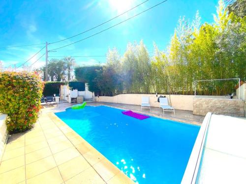 - une piscine bleue avec des chaises dans l'arrière-cour dans l'établissement Villa Oscar, au Cannet