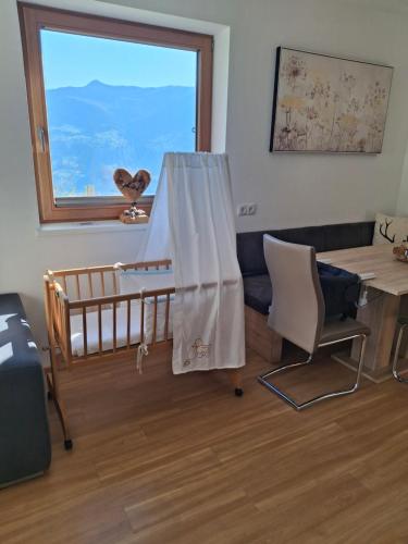 a room with a crib and a table and a window at Ferienwohnung Oberkreut in Fügenberg
