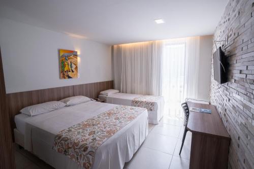 a hotel room with two beds and a television at Bessa Beach Hotel in João Pessoa