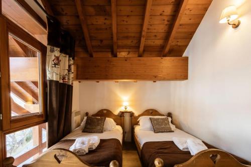 deux lits dans une chambre avec plafonds en bois dans l'établissement Les Chalets D'adrien - 5 pièces duplex 10 personnes 4 exposé ouest MAE-8864, à Valloire