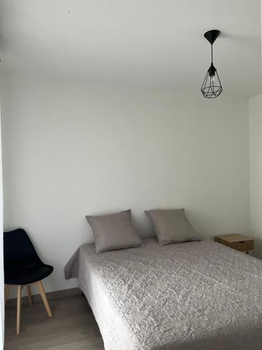 - une chambre blanche avec un lit et une chaise noire dans l'établissement Appartement plus place de parking en sous sol privatif, à Ajaccio