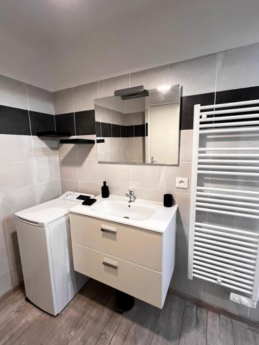 une salle de bain blanche avec un lavabo et un miroir dans l'établissement Appartement plus place de parking en sous sol privatif, à Ajaccio
