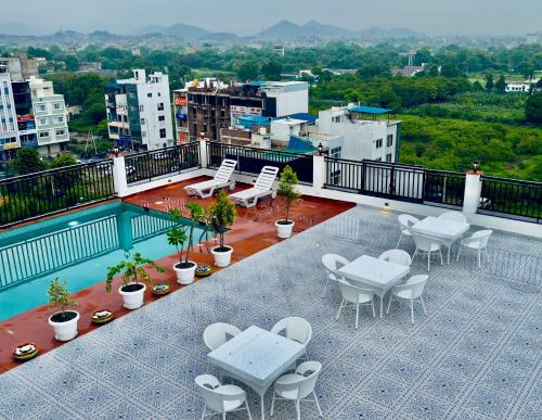 a balcony with tables and chairs on a building at The Glance inn Udaipur by NAINA STAYCATION - Rooftop swimming pool ! prime location ! most awarded ! big parking ! in Udaipur