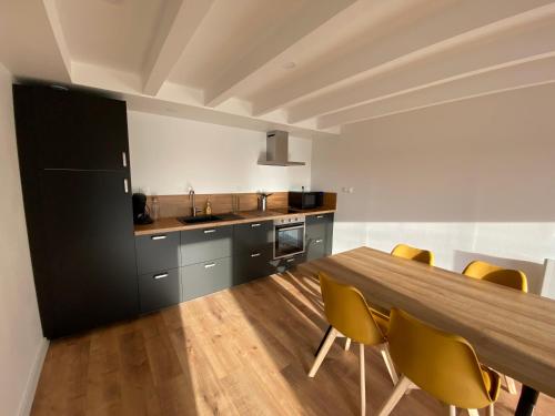 une cuisine avec une table en bois et des chaises jaunes dans l'établissement Lodge de Penfrat, une parenthèse en campagne aux portes de la ville, à Quimper
