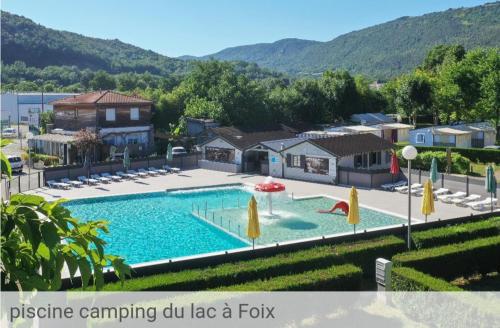 une grande piscine avec des parasols et une maison dans l'établissement Petit chalet 5 personnes, à La Celle-sous-Gouzon
