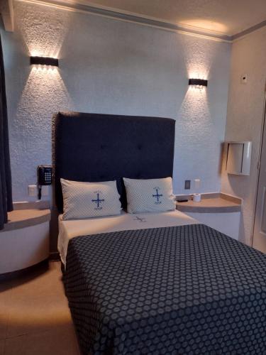a bedroom with a large bed with two cross pillows at Hotel Astur in Guadalajara