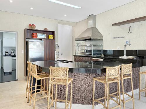 a kitchen with a black counter and chairs in it at 200m from the Beach 9 Qts AC Pool Grill in Guarujá
