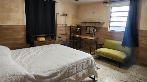 a bedroom with a bed and a chair and a window at La Casa del Arbol in Chelem
