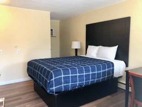 a hotel room with a bed with a blue plaid blanket at Gratiot View Motel in Saginaw