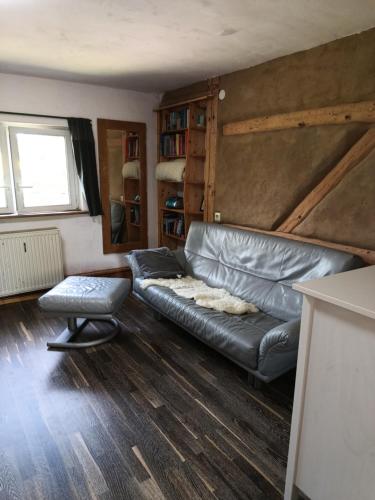 a living room with a leather couch and a chair at Landwohnung Ruppersdorf in Sachsen in Herrnhut