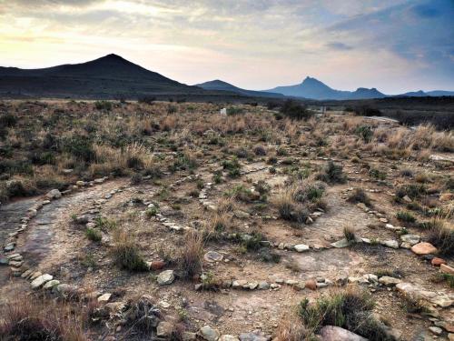 a field with rocks and mountains in the distance at Ganora Guest Farm, Camping and Excursions in Nieu-Bethesda