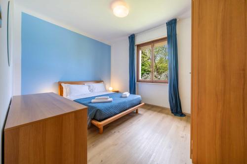 a bedroom with a blue bed and a window at Darina - Immobiliare Azzurra in Lazise