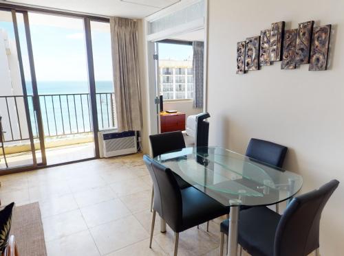 a dining room with a glass table and chairs at 36th-Floor Oceanview Suite--Full Kitchen, Stylish Comfort & Great Value (23602) in Honolulu