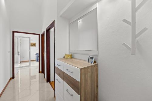 a bathroom with a wooden vanity and a white wall at Apartman Lorena in Fažana