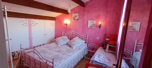 - une chambre avec des murs roses et un lit dans l'établissement Maison, à Sérignan