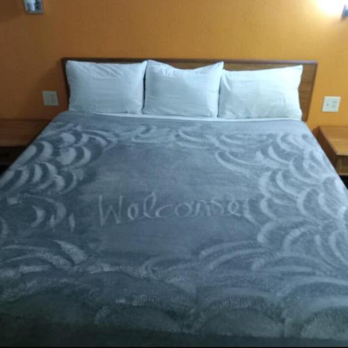 a bed in a hotel room with a blue comforter at King Bed Hotel Studio 140 in Livingston