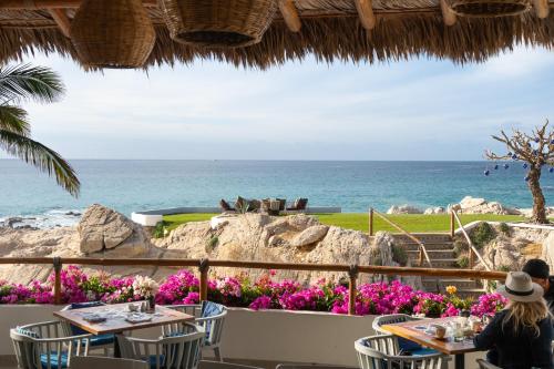 a woman sitting at a table looking out at the ocean at Mar del Cabo By Velas Resorts Adults Only in San José del Cabo