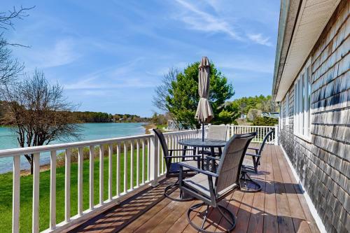 a deck with a table and chairs and an umbrella at Wiggly Bridge Landing in York Harbor