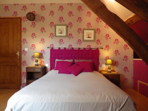 a bedroom with a white bed with pink pillows at Ferme Clatot in Les Trois Pierres