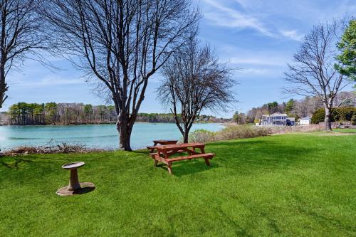 a picnic table and a bench in the grass by the water at Wiggly Bridge Landing in York Harbor
