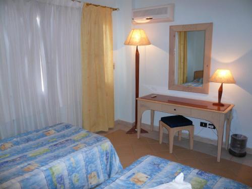 una camera da letto con scrivania, letto e specchio di Logaina Sharm Resort Apartments a Sharm El Sheikh