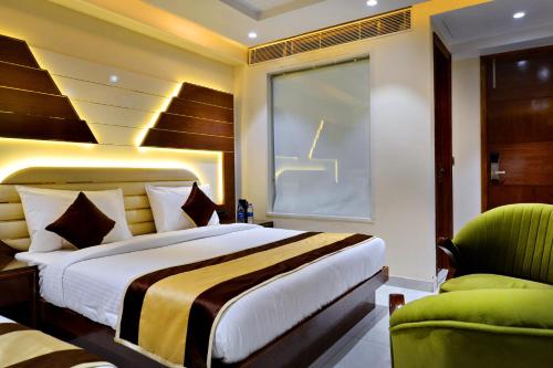 a bedroom with a large bed and a green chair at Hotel Grand Plaza in City Centre - Walking Distance From New Delhi Railway Station and Connaught Place in New Delhi