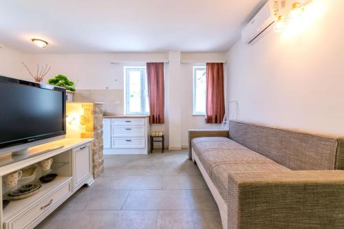 a living room with a couch and a flat screen tv at Apartments Lemon tree in Postira