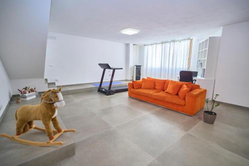 a living room with an orange couch and a dog on the floor at Rimini, 4 Camere con Giardino Privato e Parcheggio Gratuito, Relax a 10 Minuti dal Mare in Casalecchio