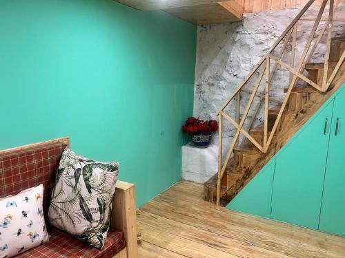 a room with a staircase with blue walls and a couch at Living Good - A Himalayan Boutique Stay in Gushaini
