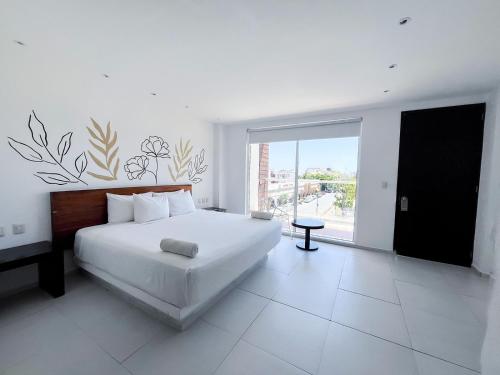 a white bedroom with a bed and a large window at Cache Hotel Boutique - Adults Only in Playa del Carmen