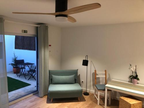 a living room with a green chair and a ceiling fan at Nareia in Vila Nova de Milfontes