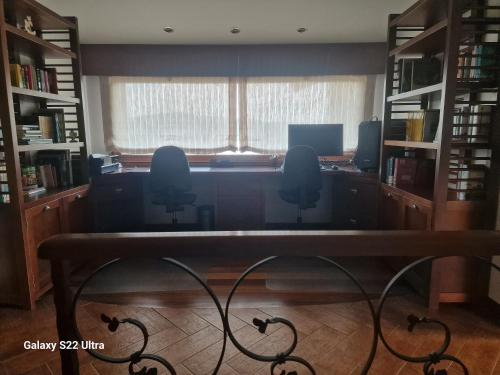 an office with a desk in a library with a window at O Piñón in Santa Cristina de Cobres