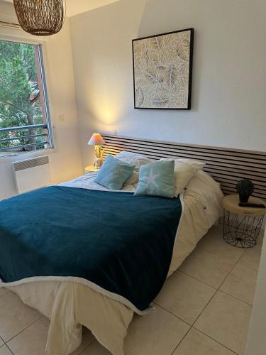 une chambre avec un grand lit avec des draps bleus dans l'établissement L éden mer et piscine appartement 53 m2, à Saint-Aygulf