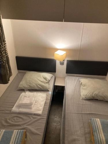 Cette chambre dispose de 2 lits et d'une lumière sur le mur. dans l'établissement Mobil Home Argelès, à Argelès-sur-Mer