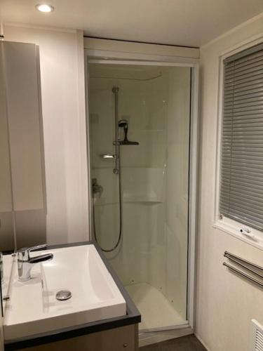 La salle de bains est pourvue d'une douche et d'un lavabo blanc. dans l'établissement Mobil Home Argelès, à Argelès-sur-Mer