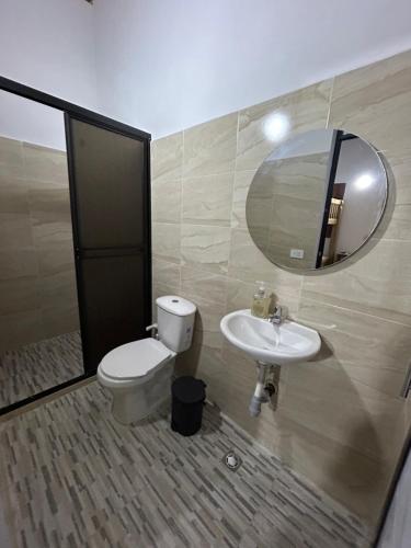 a bathroom with a toilet and a sink and a mirror at Hotel Los Molinos in Puerto Triunfo