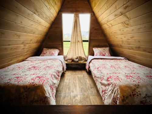 two beds in a wooden room with a window at La Encantada Cabañas in Cajamarca
